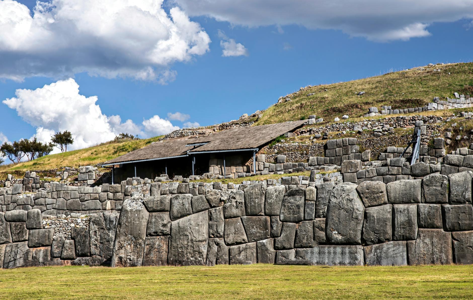 Explore the historic stone walls of Sacsayhuamán against a vibrant blue sky and lush - Peru holidays by Travelisto.com
